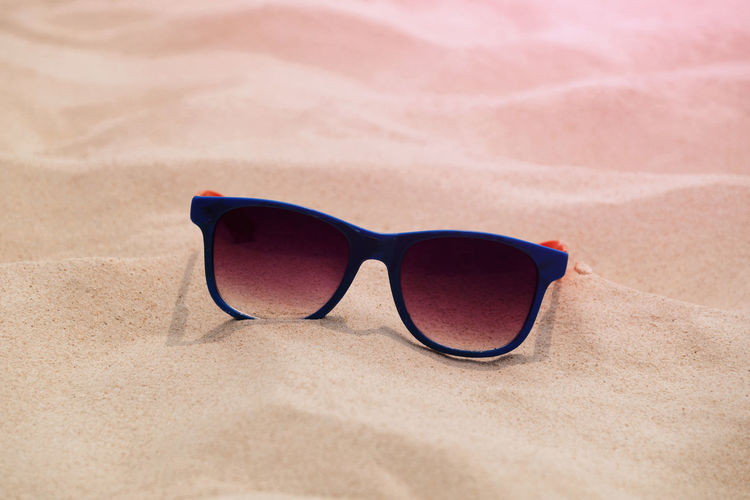 Close-up of sunglasses on sand
