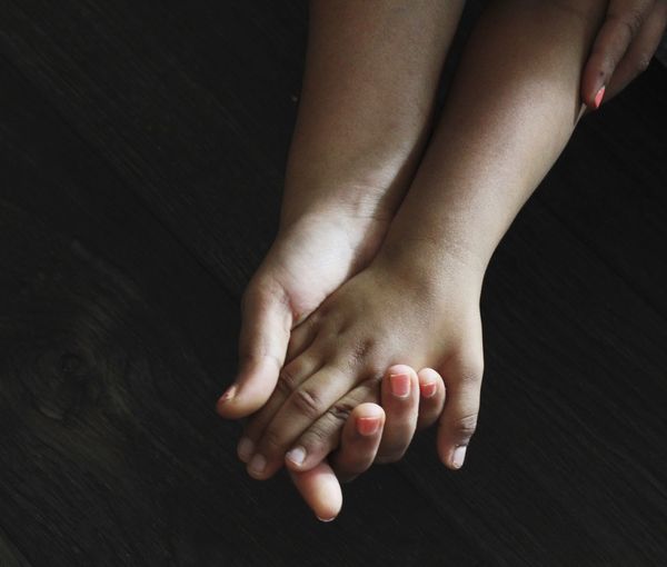 Cropped image of mother and son holding hands on table