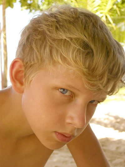 Close-up portrait of shirtless boy at beach