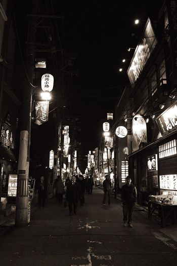 People walking on illuminated street at night