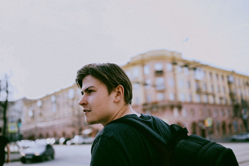 Portrait of young man looking away against sky