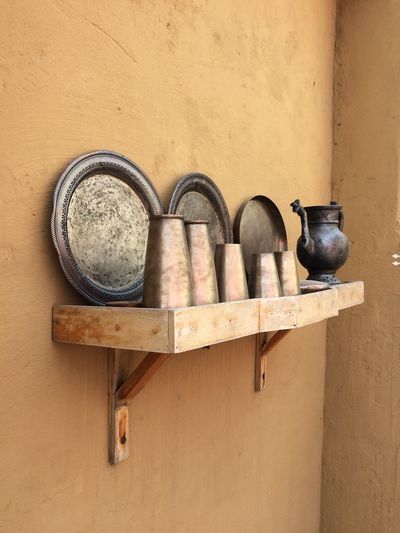 Old utensils and plates on shelf against wall