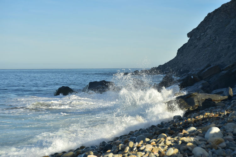 Pacific ocean wave splashing against rocks  below rocky cliff face in baja california sur, mexico