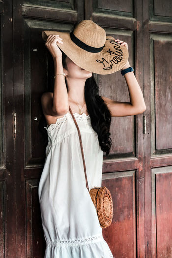 Midsection of woman wearing hat standing against entrance