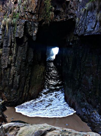 Rock formation in sea seen through tunnel