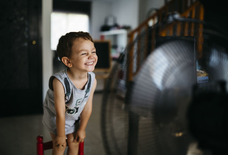 Grinning little boy standing in front of ventilator