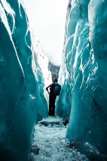 Hiker with backpack walking in ice cave