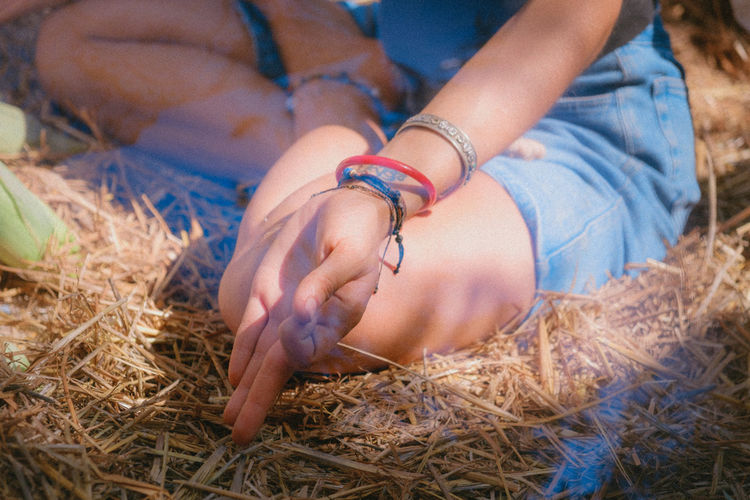 Low section of woman meditation while sitting on hay