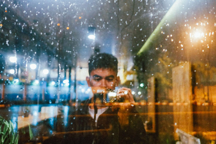 Portrait of man using mobile phone at window