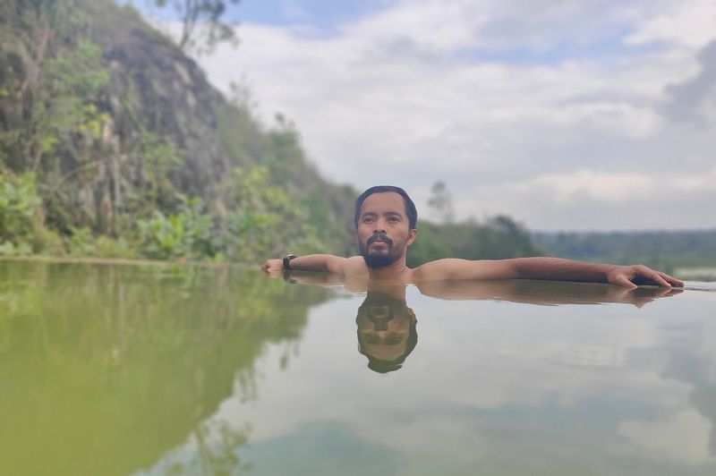 Portrait of smiling man in lake against sky
