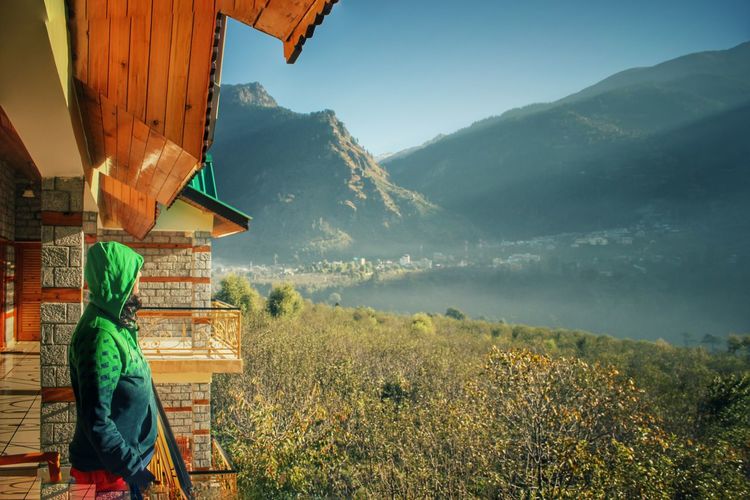 Side view of woman standing in balcony against mountains at manali