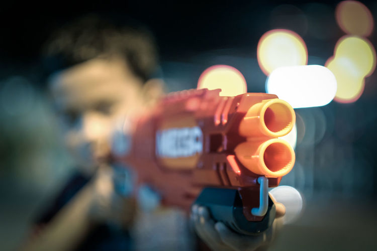 Close-up of boy holding squirt gun at night
