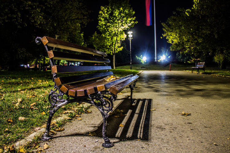 Empty bench in park at night