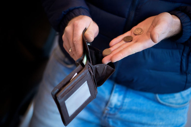 Midsection of man putting coins in wallet