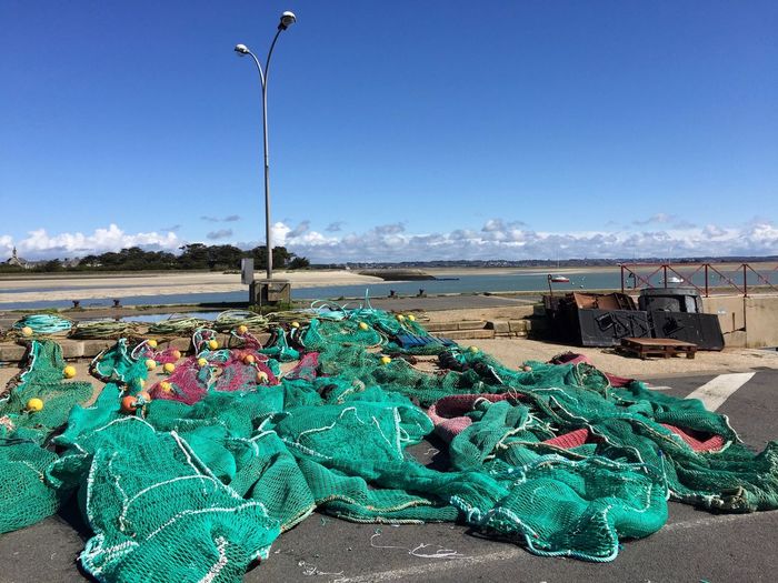 Multi colored fishing gear and nets on beach against blue sky