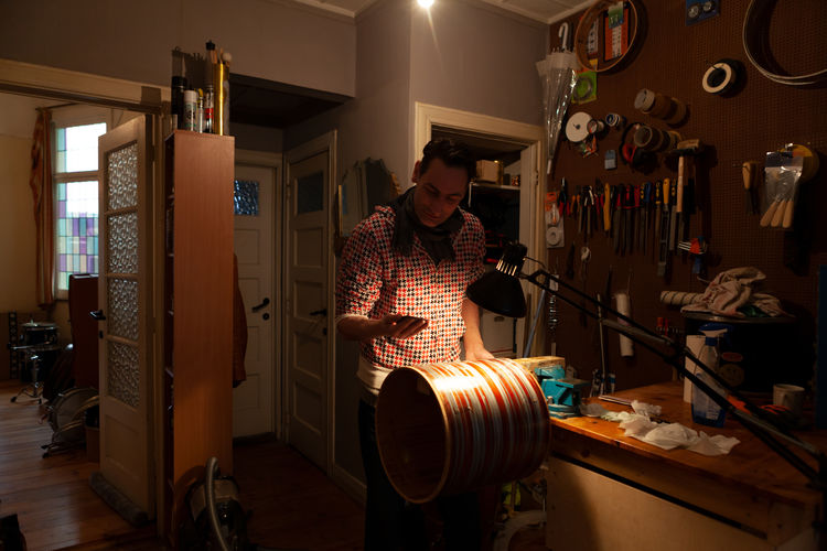 Percussionist in his workshop - drums maker building a musical instrument - craftsman repairing drum