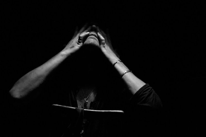 Man covering eyes with hands against black background