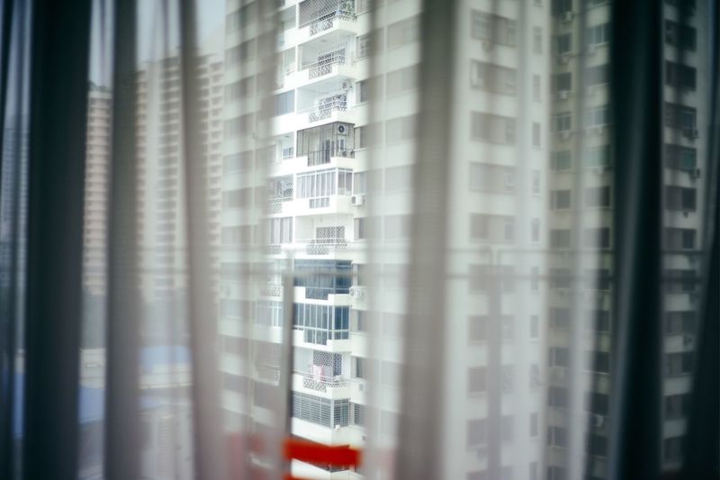 Apartment building seen through window curtain