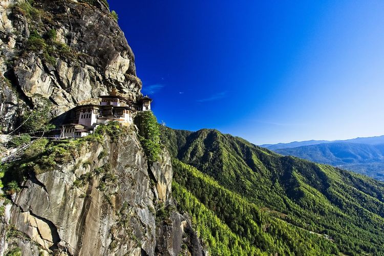 Scenic view of tigers nest monastery with mountains against blue sky