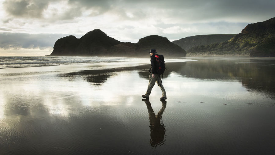 Full length of man walking on beach against sky