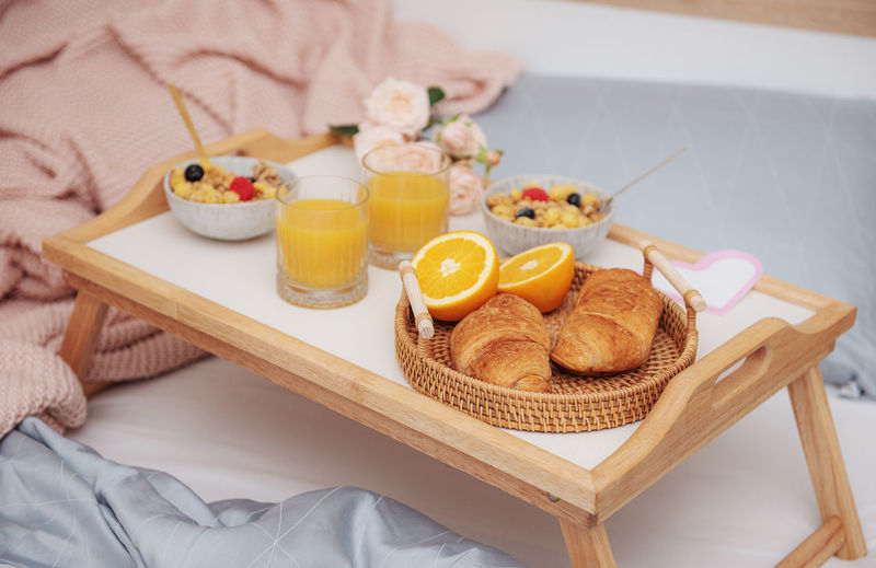 Romantic breakfast with croissants, orange juice and rose flowers.