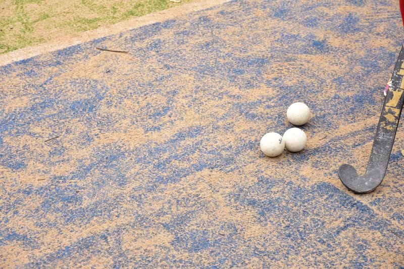High angle view of hockey stick and balls on field