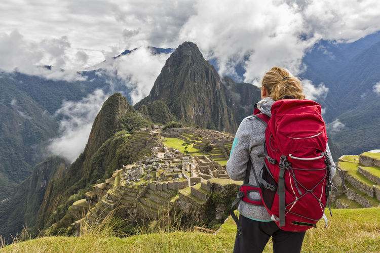 Peru, andes, urubamba valley, tourist with red backpack at machu picchu with mountain huayna picchu