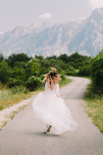 Rear view of bride running on road