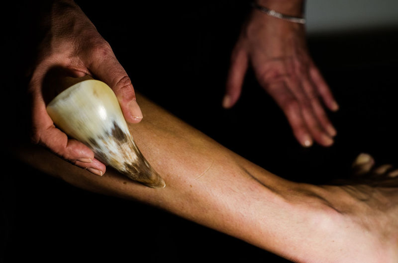 Cropped hand of massage therapist massaging human leg