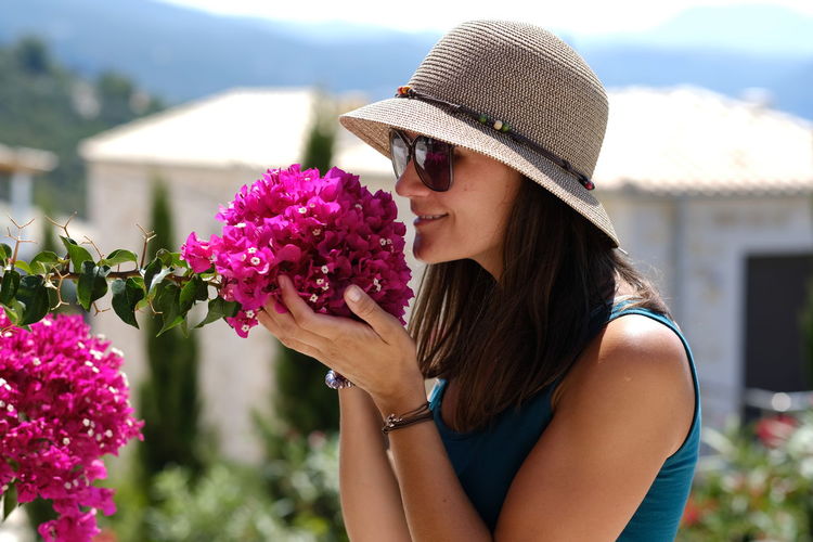 Close-up of woman smelling pink flowers blooming outdoors