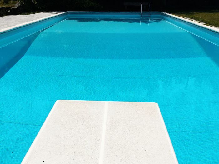 Diving board by blue swimming pool