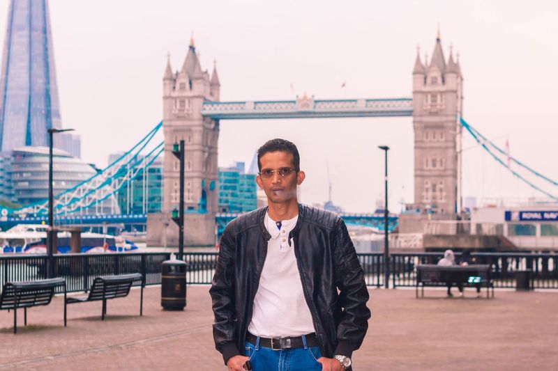 Portrait of man standing against tower bridge in city