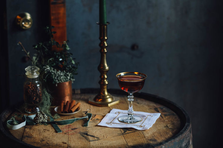 Dark still life with manhattan cocktail on whiskey barrel