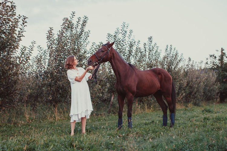 Full length of woman standing with horse against plants