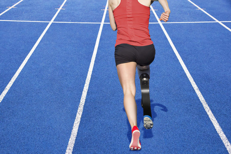 Low section of woman with running artificial leg on track