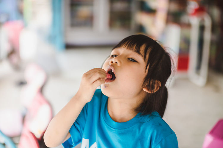 Close-up of cute girl eating ice cream cone in store