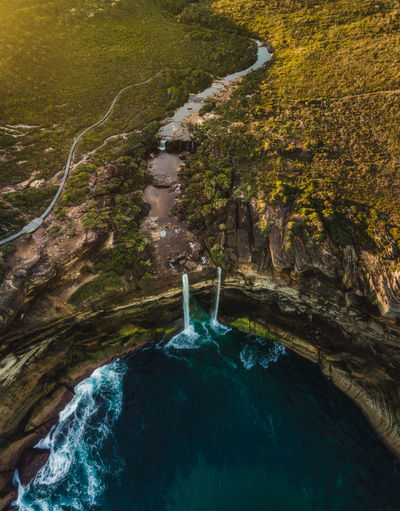 Drone high angle aerial of australian coastal landscape with iconic waterfall into the ocean