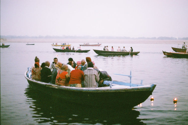 People on boat moored in sea against clear sky