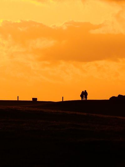 Silhouette man on field against orange sky