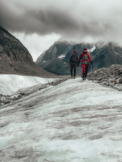 Two mountaineers descending glacier in france under dramatic clouds