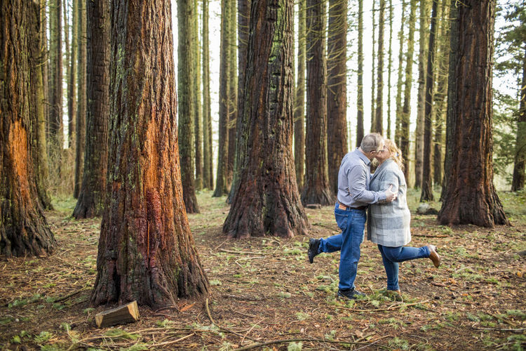 Romantic retired couple kissing in the woods.