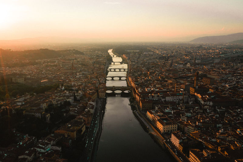 Aerial view of bridges over river in city during sunset