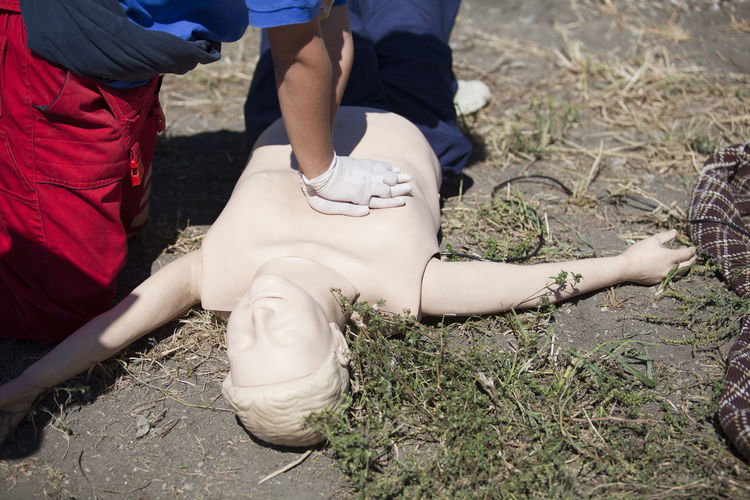 Midsection of man practicing cpr on dummy on field