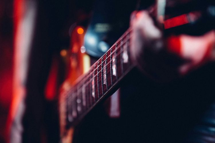 Midsection of person playing guitar on stage