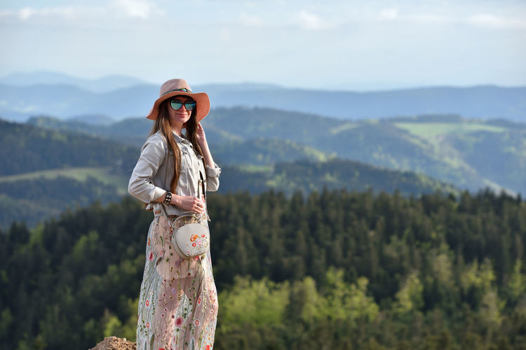 Woman wearing hat and sunglasses while standing against mountain