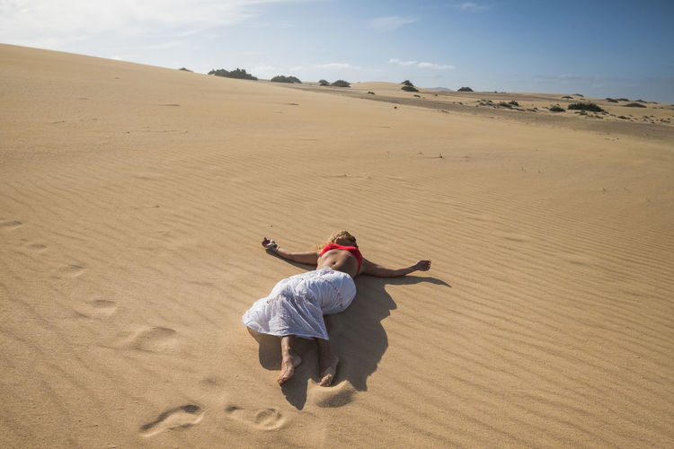 Full length of woman lying at desert