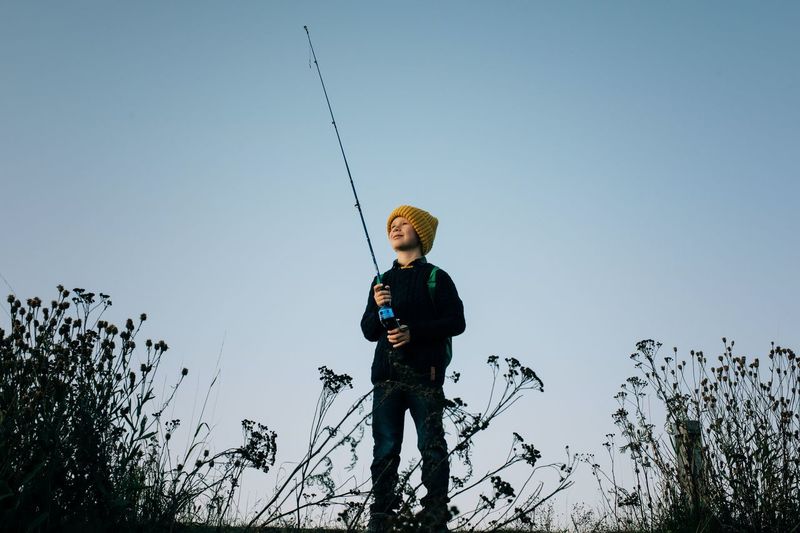 Young boy happily fishing at sunset alone