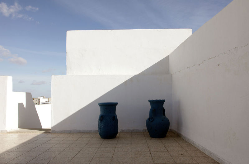 Urns in front of white wall on building terrace
