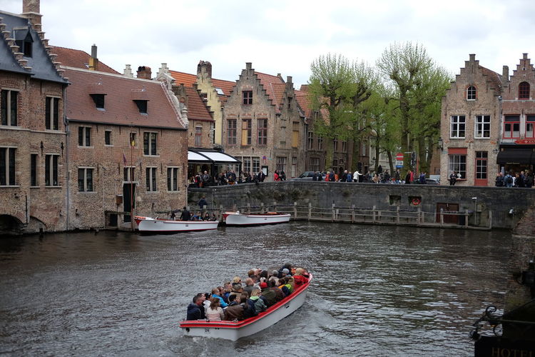 People on boats in water against buildings