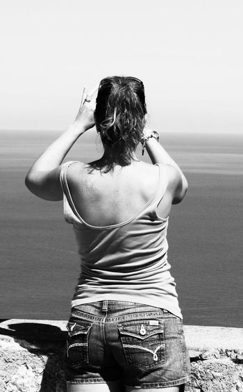 Rear view of woman at beach against sky